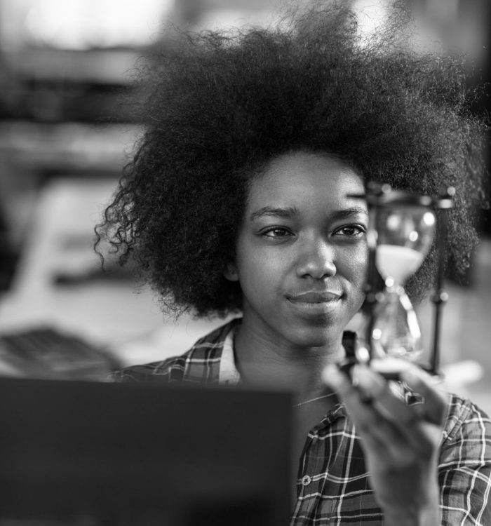 portrait of a young successful African American beautiful woman who enjoys spending a quality and joyful time while working in a large modern office