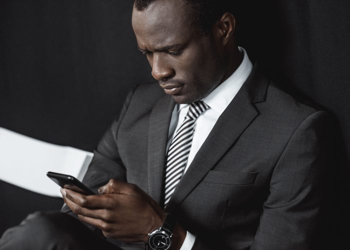 portrait of focused african american businessman using smartphone